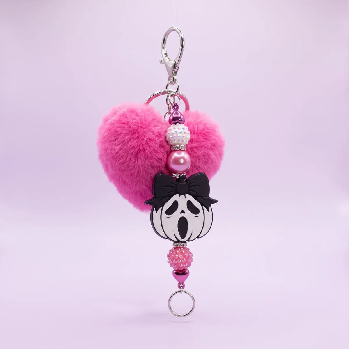 Pink Pom Ghost Charm hanging from its silver clasp — a hot pink heart pom-pom above a white ghost charm wearing a black bow, strung with pink sparkle and pearl beads