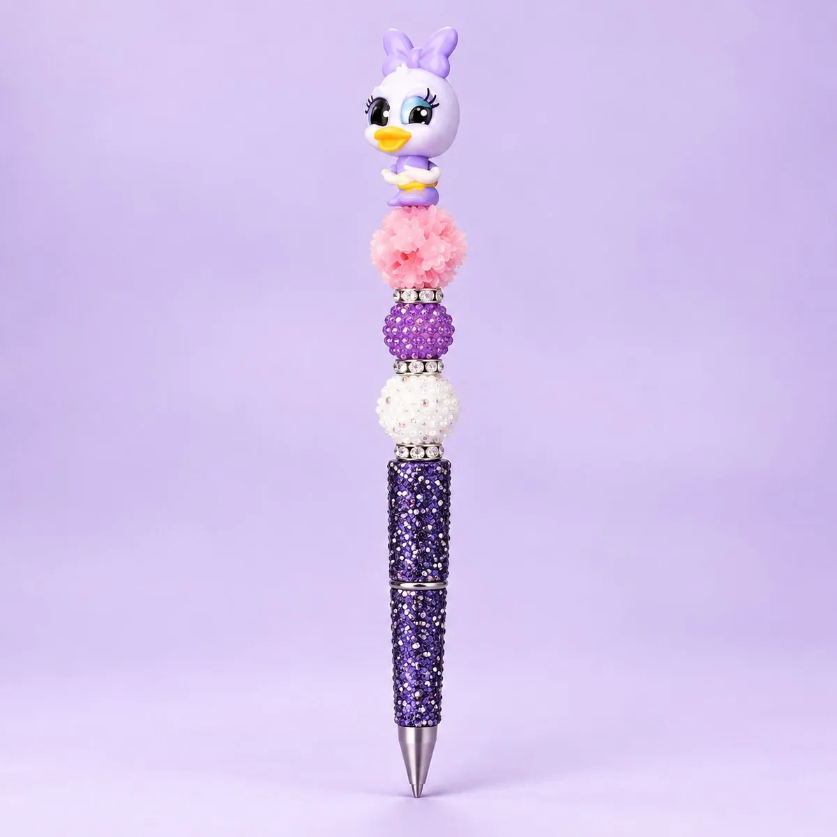 Lilac Duck Beaded Pen on a pale lavender backdrop — beaded pen with a lilac-and-white girl duck topper with a bow, pink flower, purple and white beads, and a dark purple glitter barrel