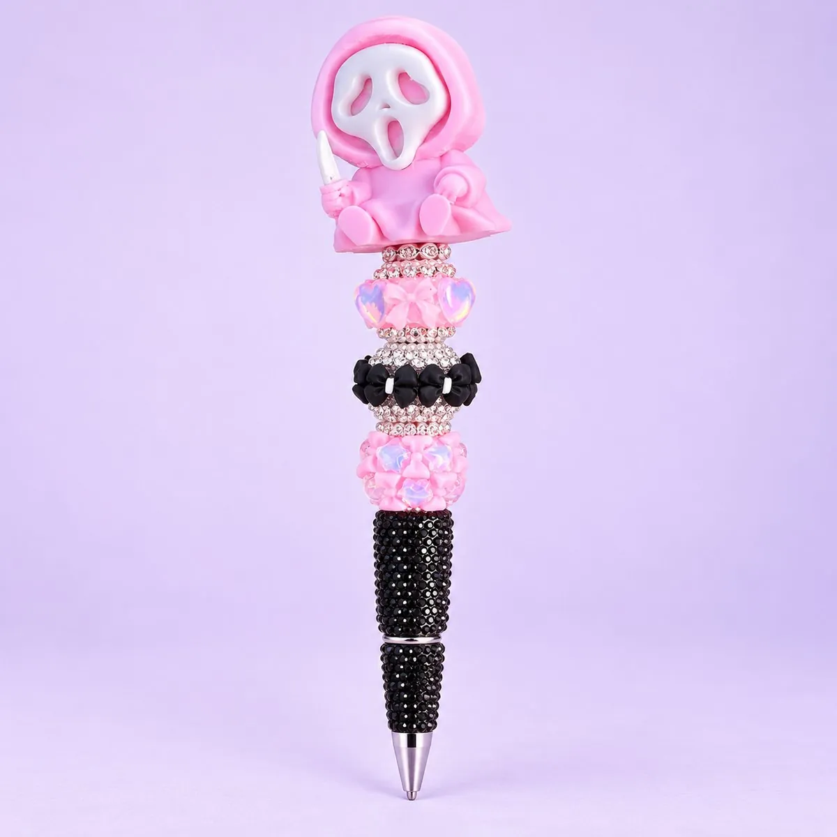 Pink Ghost Bling Pen on a pale lavender backdrop — a pink hooded ghost figure topper with a white mask, pink bow, black and pink rhinestone beads, and a black rhinestone barrel