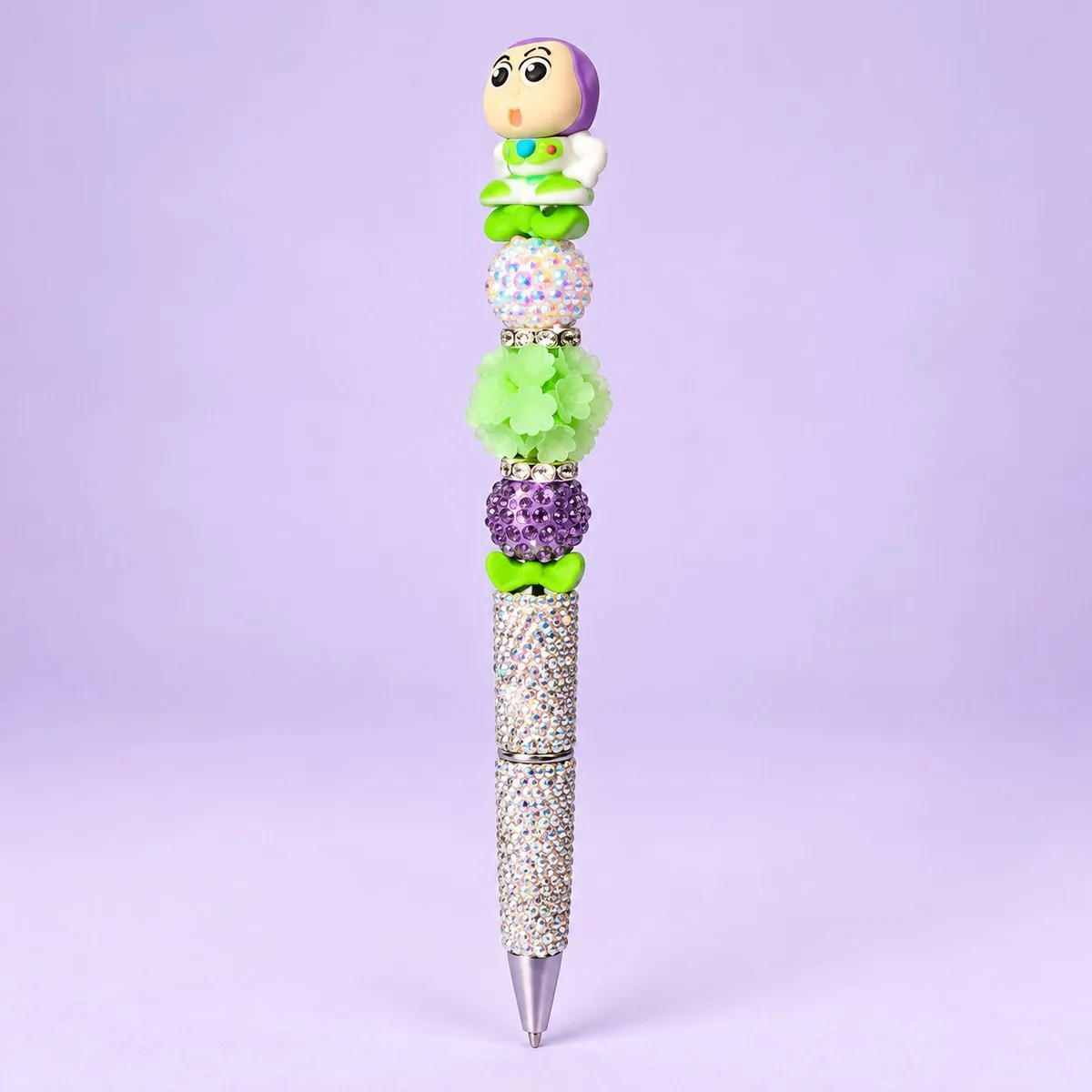 Space Ranger Beaded Pen on a pale lavender backdrop — beaded pen with a white-and-green space ranger topper, pale green, lavender and green flower beads, and a silver rhinestone barrel