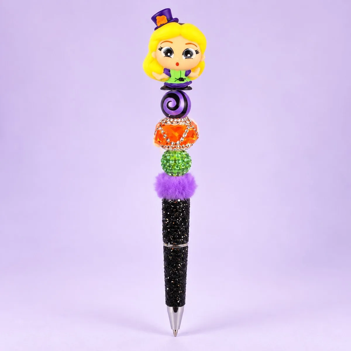 Wonderland Witch Beaded Pen on a pale lavender backdrop — beaded pen with a blonde girl topper in a small purple hat, a purple swirl bead, orange, green and purple fluffy beads, and a black glitter barrel