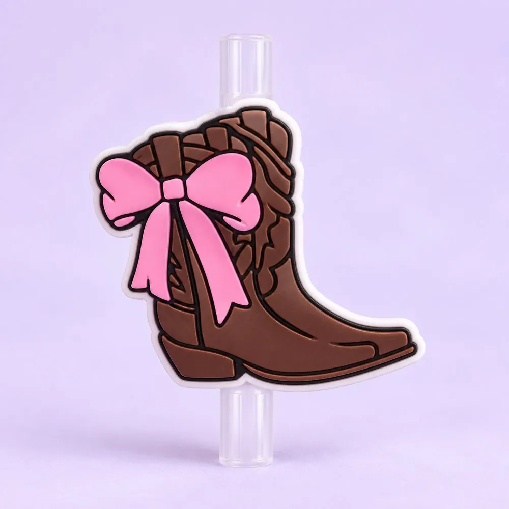 Cowgirl Boot Topper on a clear straw, pale lavender backdrop — shaped like a brown cowgirl boot with a pink bow
