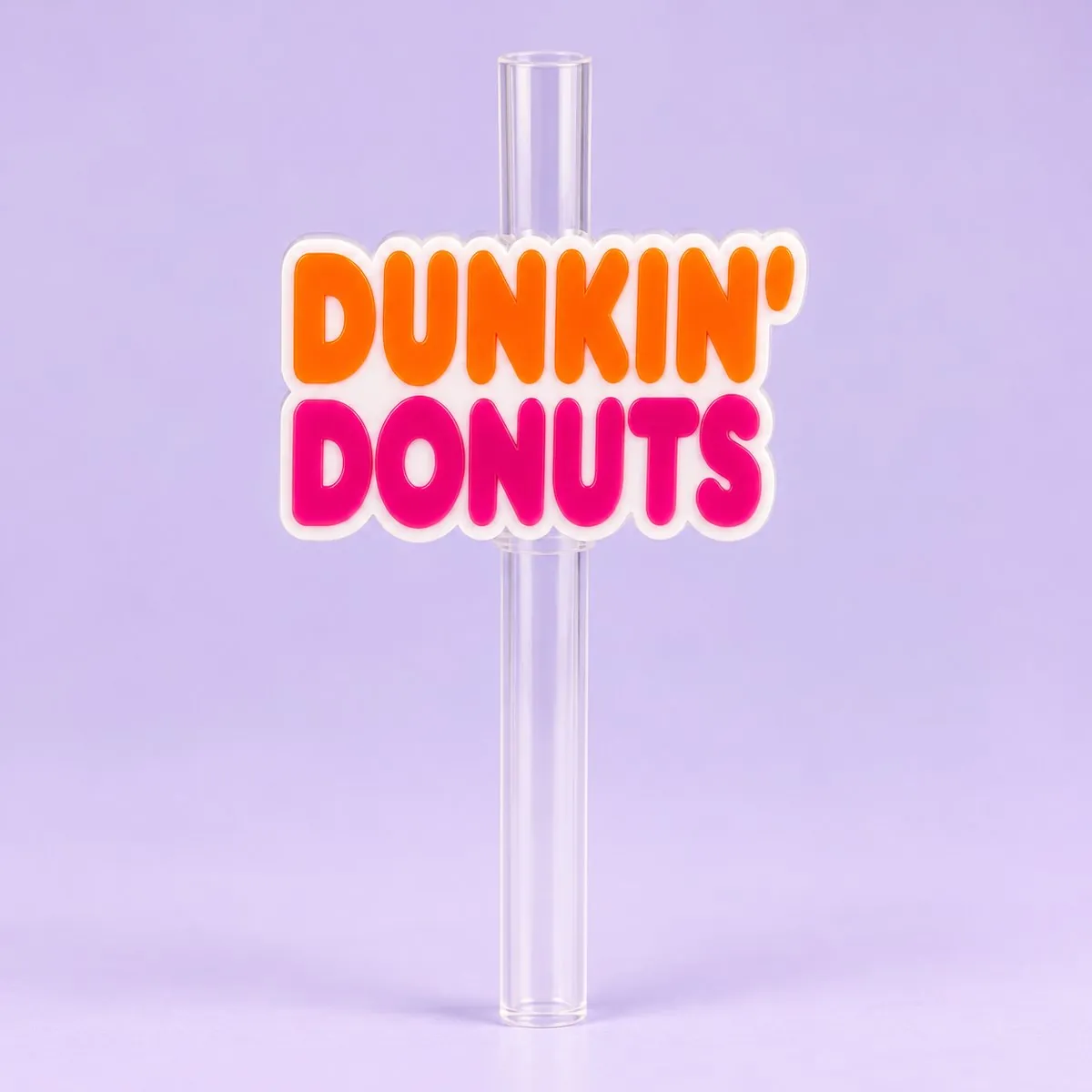 Donut Shop Straw Topper on a pale lavender backdrop — a flat cut-out straw charm of bold orange and pink bubble lettering reading DUNKIN' DONUTS with a white outline, sitting on a clear straw