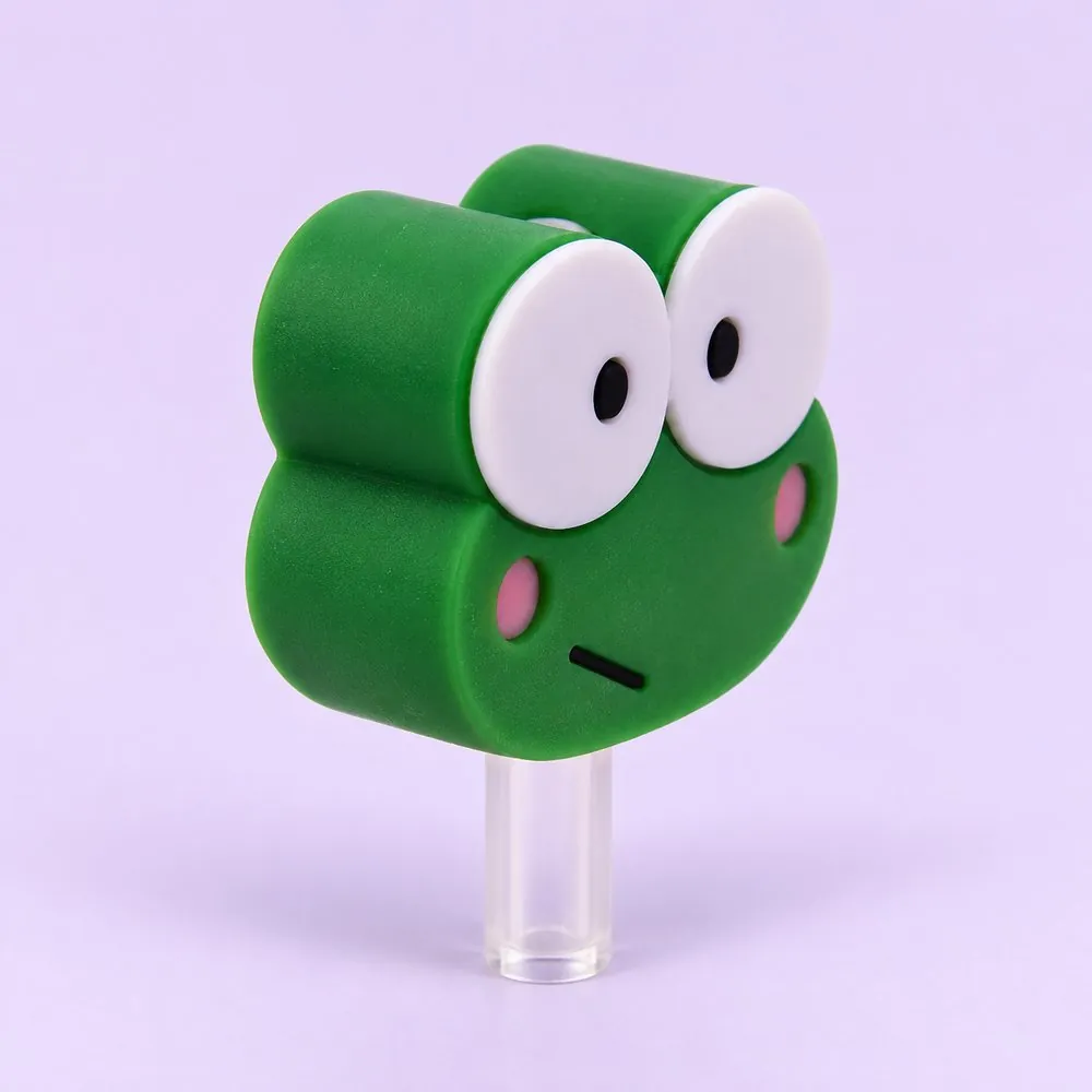 Green Frog Topper on a clear straw, pale lavender backdrop — shaped like a green cartoon frog head with big white eyes