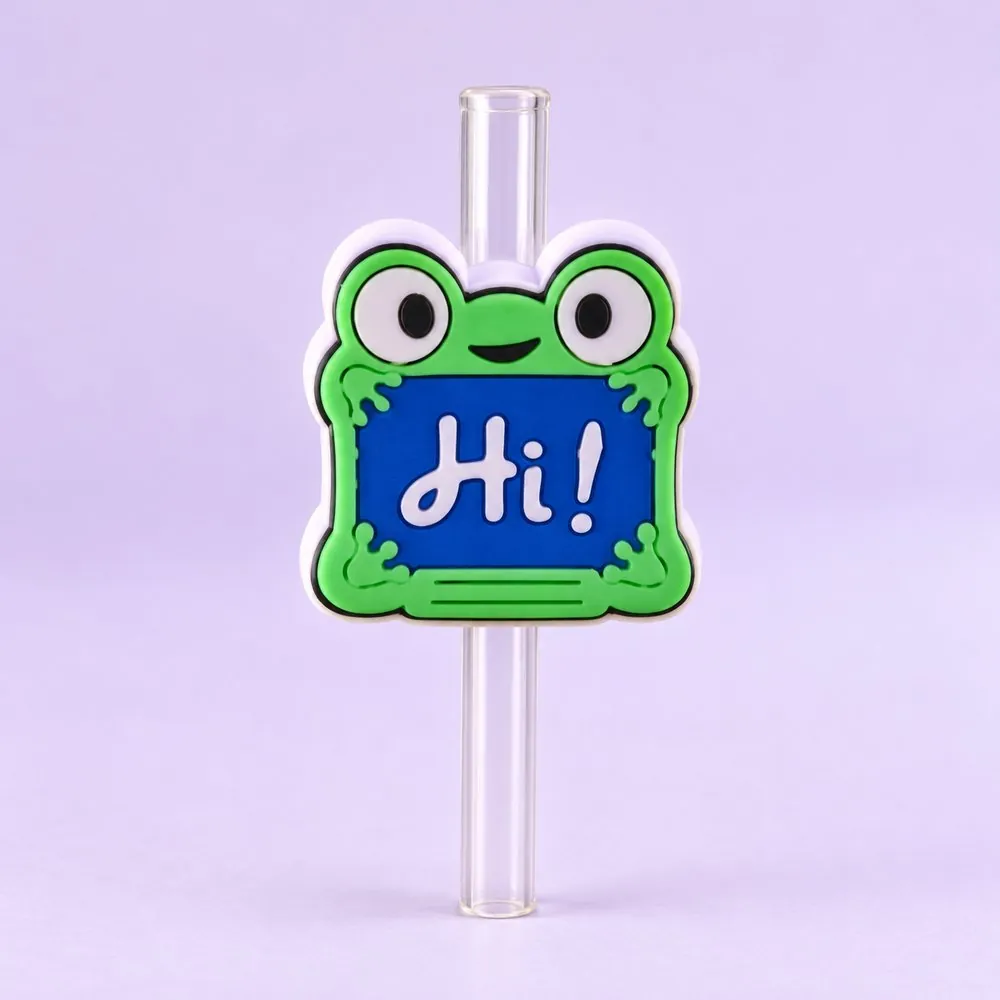 Hi Frog Topper on a clear straw, pale lavender backdrop — shaped like a green cartoon frog holding a blue sign that says Hi!
